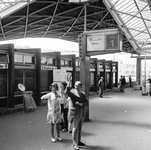 803860 Afbeelding van enkele uitzwaaiende personen op het perron van het N.S.-station Tilburg te Tilburg.